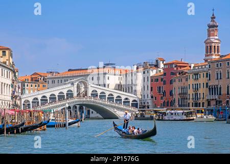 Brücke Ponte di Rialto über den Canal Grande und Gondoliere in einer traditionellen Gondel mit Touristen in Venedig, Venetien, Norditalien Stockfoto