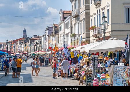 Touristen und Souvenirläden/Souvenirläden in der Stadt Chioggia auf einer kleinen Insel am Eingang zur Lagune von Venedig, Veneto, Norditalien Stockfoto