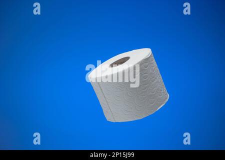 Generische mehrlagige weiße Toilettenpapierrolle. Nahaufnahme im Studio, isoliert auf blauem Hintergrund, keine Menschen. Stockfoto