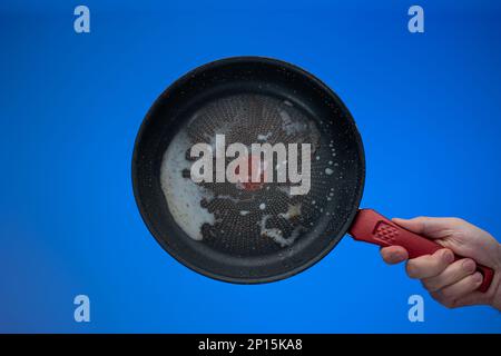 Dreckige, ölig verbrannte Bratpfanne aus Metall, die von Männern in der Hand gehalten wird. Stockfoto