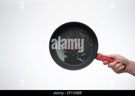 Dreckige, ölig verbrannte Bratpfanne aus Metall, die von Männern in der Hand gehalten wird. Stockfoto