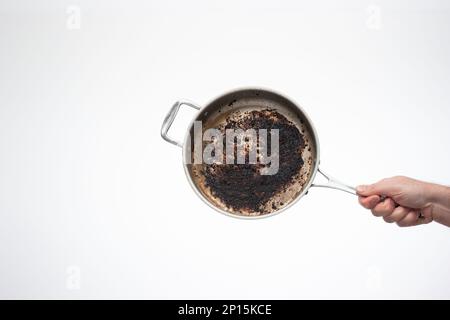 Dreckige, ölig verbrannte Bratpfanne aus Metall, die von Männern in der Hand gehalten wird. Stockfoto