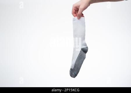 Eine trockene und saubere Baumwollsocke, die von einem weißen Mann in der Hand gehalten wird. Nahaufnahme des Studios, isoliert auf weißem Hintergrund. Stockfoto
