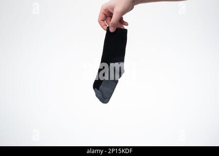 Eine trockene und saubere Baumwollsocke, die von einem weißen Mann in der Hand gehalten wird. Nahaufnahme des Studios, isoliert auf weißem Hintergrund. Stockfoto