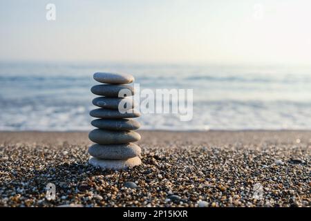 Ausgewogene Kieselpyramide am Strand. Selektiver Fokus Abstraktes Bokeh mit Sea im Hintergrund. Zen Steine am Strand, Meditation, Spa, Harmonie. Stockfoto