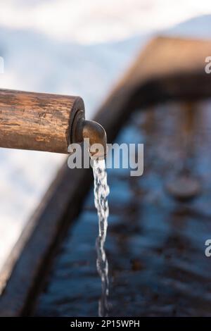 Fließendes Trinkwasser aus einem Waldbrunnen-Hahn im Winter in der Schweiz reinigen. Stockfoto