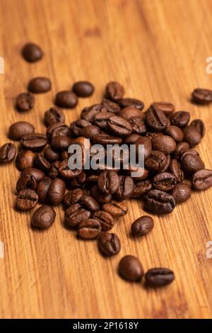 Braune geröstete Kaffeebohnen, kleiner Stapel auf einem Holzbrett-Makroshot. Stockfoto