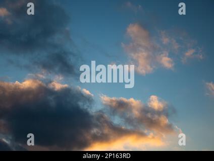 Dramatische Landschaft bei Sonnenuntergang, rosa und orangefarbene Puffwolken. Stockfoto