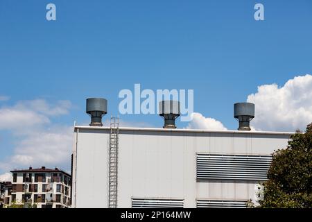 Drei graue Metallrohre eines Industriegebäudes auf blauem Metallhintergrund Stockfoto