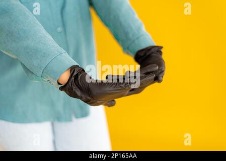 Schwarzer Nitril-Schutzhandschuh auf gelbem Hintergrund. Stockfoto