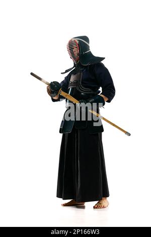 Porträt eines Mannes, eines professionellen Kendo-Athleten in Uniform, der mit einem Shinai-Schwert vor weißem Studiohintergrund posiert Stockfoto