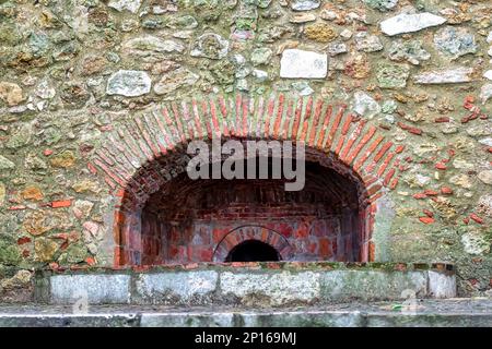 Eine Backsteinbogenstruktur in der Steinmauer der alten Festung. Stockfoto