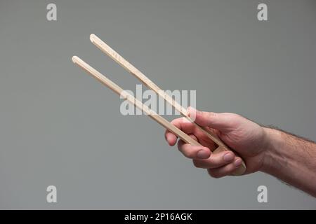 Weiße männliche Hand mit einer hölzernen zange Nahaufnahme isoliert auf grauem Hintergrund. Stockfoto