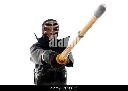 Kämpfer. Porträt eines Mannes, eines professionellen Kendo-Athleten in Uniform, der mit einem Shinai-Schwert vor weißem Studiohintergrund posiert Stockfoto