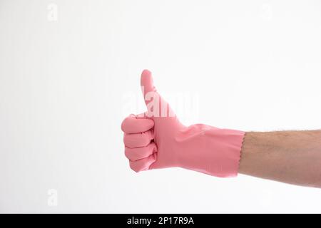 Pinkfarbener Latex-Reinigungshandschuh auf weißer männlicher Hand mit Daumen-hoch-Geste isoliert auf weißem Hintergrund. Stockfoto