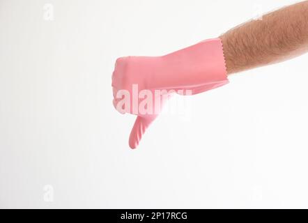 Pinkfarbener Latex-Reinigungshandschuh auf weißer männlicher Hand mit Daumen nach unten, isoliert auf weißem Hintergrund. Stockfoto
