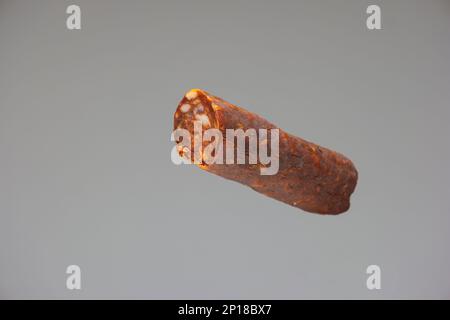 Hausgemachte ungarische geräucherte scharfe Salami Nahaufnahme Studio auf grauem Hintergrund. Stockfoto