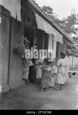 Reiseansichten von Japan und Korea, 1908. Kinder vor einem Laden, gewebte Sandalen sind ausgestellt. Stockfoto