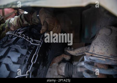 10. Bergsoldaten arbeiten zusammen, um Schneeketten auf einem HMMV in weniger als 10 Minuten zu platzieren. Die Teams konkurrieren um die schnellste Zeit, bevor sie mit der nächsten Übung fortfahren. Stockfoto