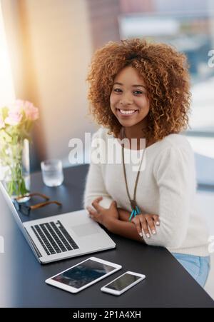 Sie nutzt jedes Tool für geschäftliche Angelegenheiten. Porträt einer jungen Geschäftsfrau, die in einem Büro an ihrem Schreibtisch sitzt. Stockfoto