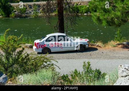 Okanogan County, Washington, USA - 25. JUNI 2022: Ein verlassenes Auto steht neben dem Fluss Stockfoto
