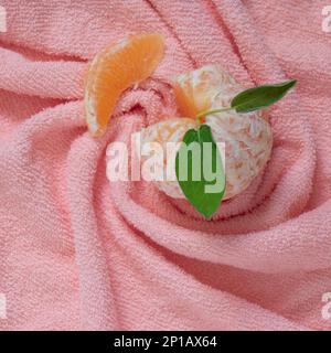 Eine Nahaufnahme einer Mandarine, die auf einem pinken Handtuch ruht Stockfoto