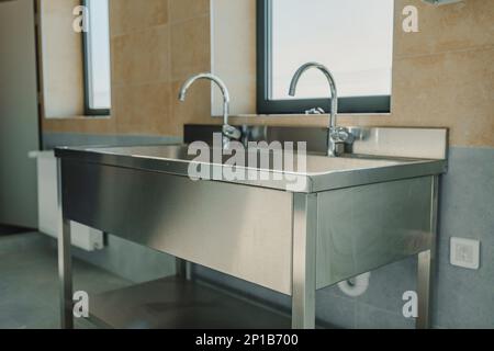 Industrielles Edelstahlwaschbecken im Badezimmer einer Werkstatt Stockfoto