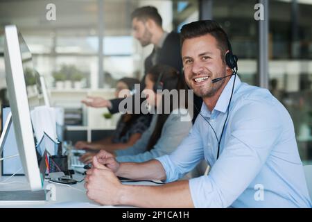 Großartiger Service macht gute Geschäfte. Porträt eines glücklichen und selbstbewussten jungen Mannes, der in einem Callcenter arbeitet. Stockfoto