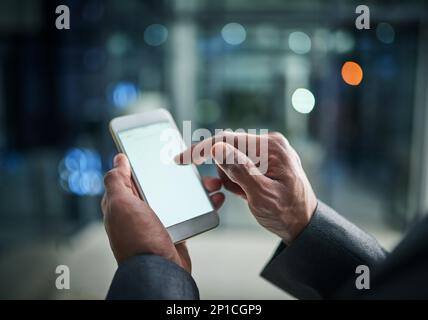 Abrufen von Business-Updates per SMS. Ausgeschnittene Aufnahme eines Geschäftsmanns, der in einem modernen Büro ein Mobiltelefon verwendet. Stockfoto