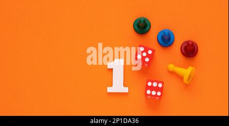 Nummer eins in Weiß mit Steinen und Spielwürfeln - Hintergrund aus orangefarbenem eva-Gummi Stockfoto