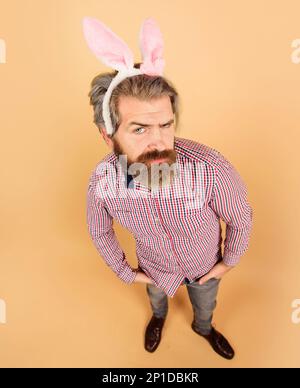 Ostermann. Ein bärtiger Kerl mit Hasenohren bereitet sich auf Ostern vor. Hasenmann in Kaninchenohren. Ein bärtiger Typ mit Hasenohnen. Kaninchenmann auf Osterurlaub Stockfoto