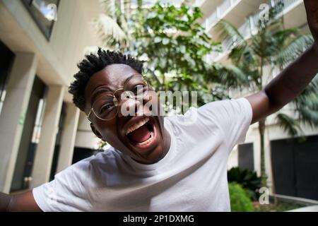 Selfie eines jungen afroamerikanischen Mannes mit offenem Mund, der vor Glück schreit. Schließen Sie die Leute ab Stockfoto