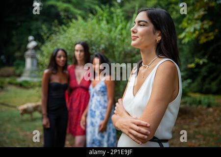 Eine junge Frau sieht mit ihren Freunden hinter sich zur Seite, ohne Fokus, ohne Weiberbegriff und Einheit. Stockfoto