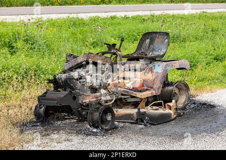 Rasentraktor durch Feuer beschädigt. Konzept für die Wartung, Reparatur und Hauseigentümerversicherung von Rasengeräten. Stockfoto