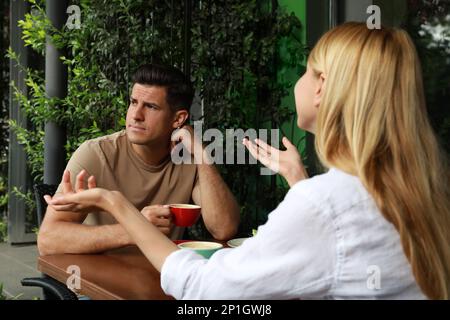 Ein Mann hat ein langweiliges Date mit einer gesprächigen Frau im Café draußen Stockfoto