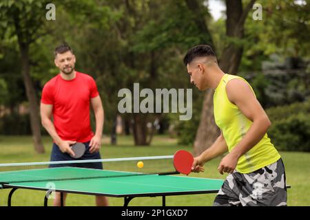 Freunde spielen im Freien Tischtennis am Sommertag Stockfoto