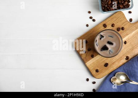 Ein Glas Milch mit Grasgelee und Kaffeebohnen auf einem weißen Holztisch, flach liegend. Platz für Text Stockfoto