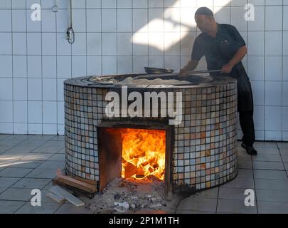 TASCHKENT, USBEKISTAN - 04. SEPTEMBER 2022: Koch rührt Reis in einem Kessel. Traditioneller Kochpilaf Stockfoto