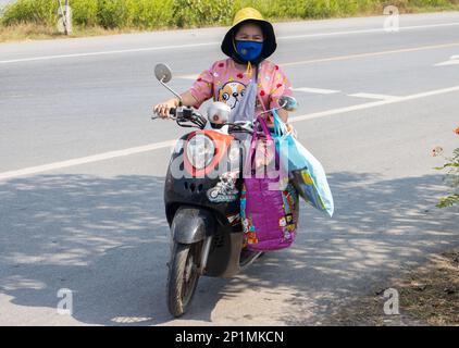 BANGKOK, THAILAND, FEBRUAR 07 2023, Eine Frau mit vielen Taschen fährt ein Motorrad Stockfoto