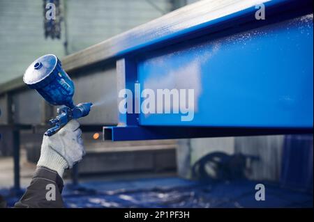 Arbeiter lackiert Metallkadaver mit Luftbürste in der Werkstatt Stockfoto
