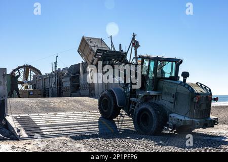 USA Marines mit dem logistischen Kampfelement, 26. Marine Expeditionary Unit (MEU), neben den USA Marine-Matrosen, Ausrüstung und Ausrüstung auf ein Landefahrzeug laden, Luftkissen während einer Strandoperation für Amphibiengeschwader/MEU Integrated Training (PMINT) im Marine Corps Base Camp Lejeune, North Carolina, 24. Januar 2023. PMINT ist die erste Phase auf See in der Zwischenstufe des MEU-Ausbildungsprogramms zur Vorbereitung des Einsatzes; es zielt darauf ab, die Interoperabilität zu verbessern und Beziehungen zwischen Marines und Seeleuten aufzubauen. Stockfoto