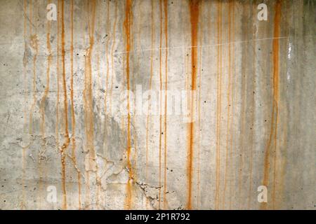 Durchgehende verwitterte Betonwand mit Rostflecken. Stockfoto