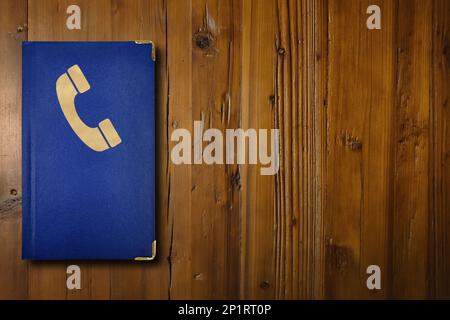 Nahaufnahme eines blauen Telefonbuchs auf einem hölzernen Schreibtisch. Stockfoto