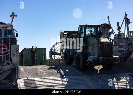 USA Marines mit Kampflogistik-Bataillon 22, 26. Marine Expeditionary Unit (MEU), neben den USA Marine-Matrosen, Ausrüstung und Ausrüstung auf ein Landefahrzeug laden, Luftkissen während einer Strandoperation für Amphibiengeschwader/MEU Integrated Training (PMINT) im Marine Corps Base Camp Lejeune, North Carolina, 24. Januar 2023. PMINT ist die erste Phase auf See in der Zwischenstufe des MEU-Ausbildungsprogramms zur Vorbereitung des Einsatzes; es zielt darauf ab, die Interoperabilität zu verbessern und Beziehungen zwischen Marines und Seeleuten aufzubauen. Stockfoto