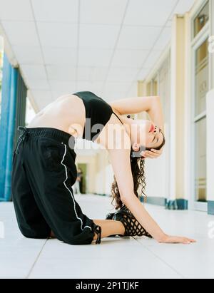 Porträt einer Tänzerin in Fersen, die Yoga-Flexibilitäten macht, einer Tanzkünstlerin Akrobatik und Flexibilitäten in Fersen. Das Tanzmädchen macht Stockfoto