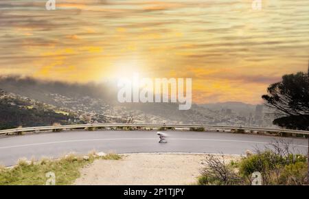 Straße, Aussicht und Sonnenuntergang mit einem Skater, der sich schnell auf einer Asphaltstraße bewegt, um in der Natur Sport zu treiben. Luftaufnahmen, Bewegungsunschärfe oder Schlittschuhlaufen und ein männlicher Sportler Stockfoto