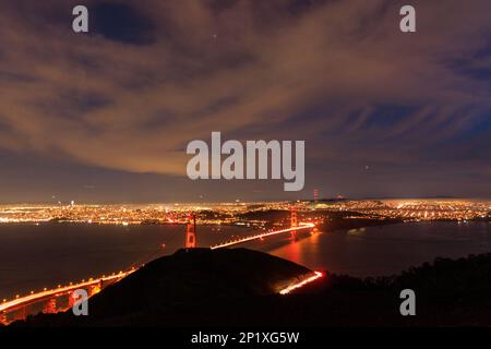 Ampeln von Autos und Verkehr auf der Golden Gate Bridge in der weitläufigen Stadt bei Nacht Stockfoto