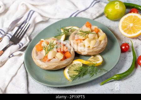 Artischocke mit Gemüse auf grauem Boden. Artischocken-Abendessen mit Olivenöl, Kartoffeln, Karotten und Zwiebeln. Gesundes Essen Stockfoto