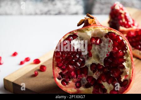 Frischer, saftiger Granatapfel, offener Granatapfel auf einem Holzbrett, Nahaufnahme. Stockfoto