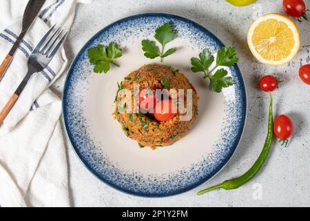 Bulgur-Salat auf grauem Hintergrund. Traditioneller türkischer bulgarischer Salat oder kısır salatası. Draufsicht Stockfoto